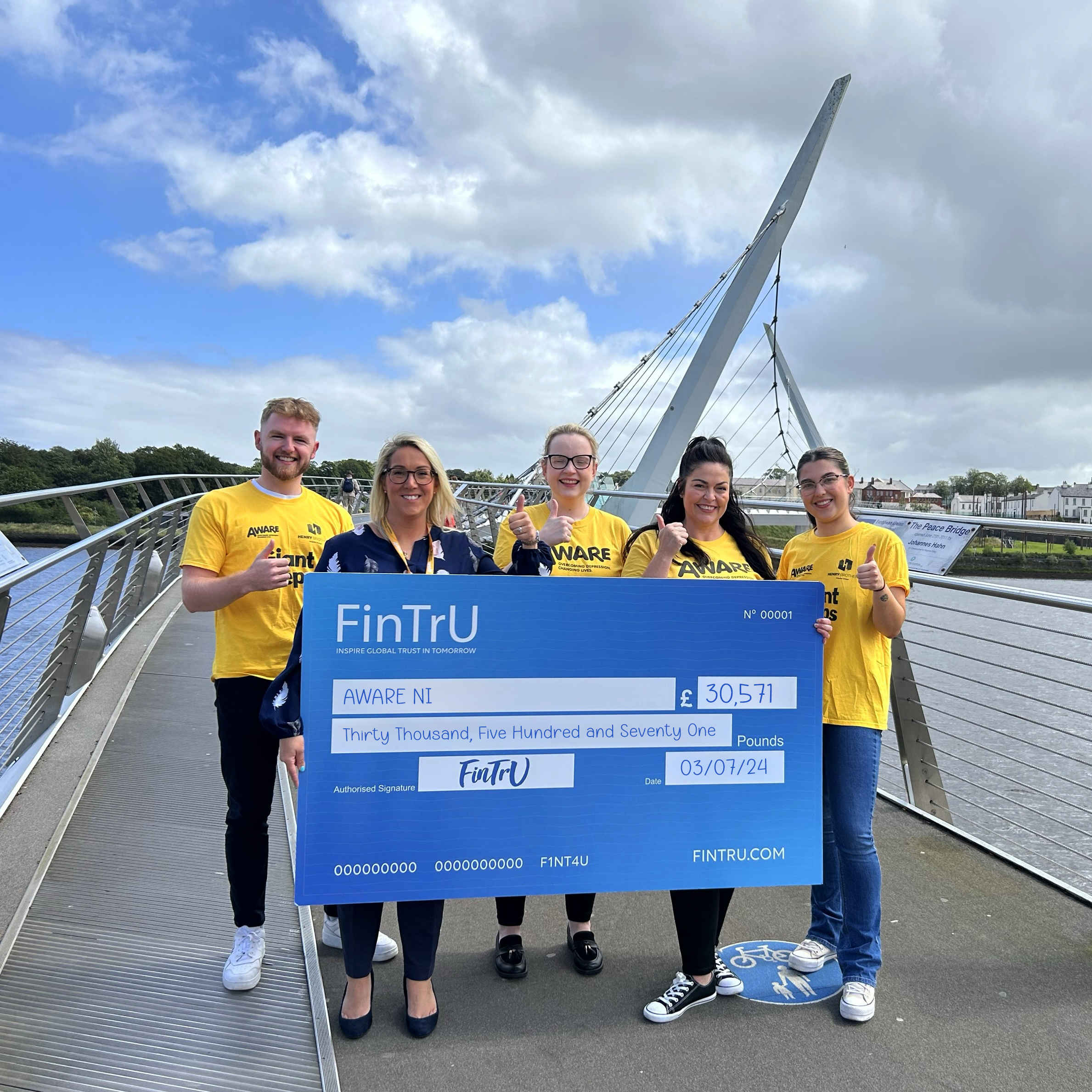 Four FinTrU employees giving to Leigh Osborne, Aware NI fundraiser head, a donation cheque 