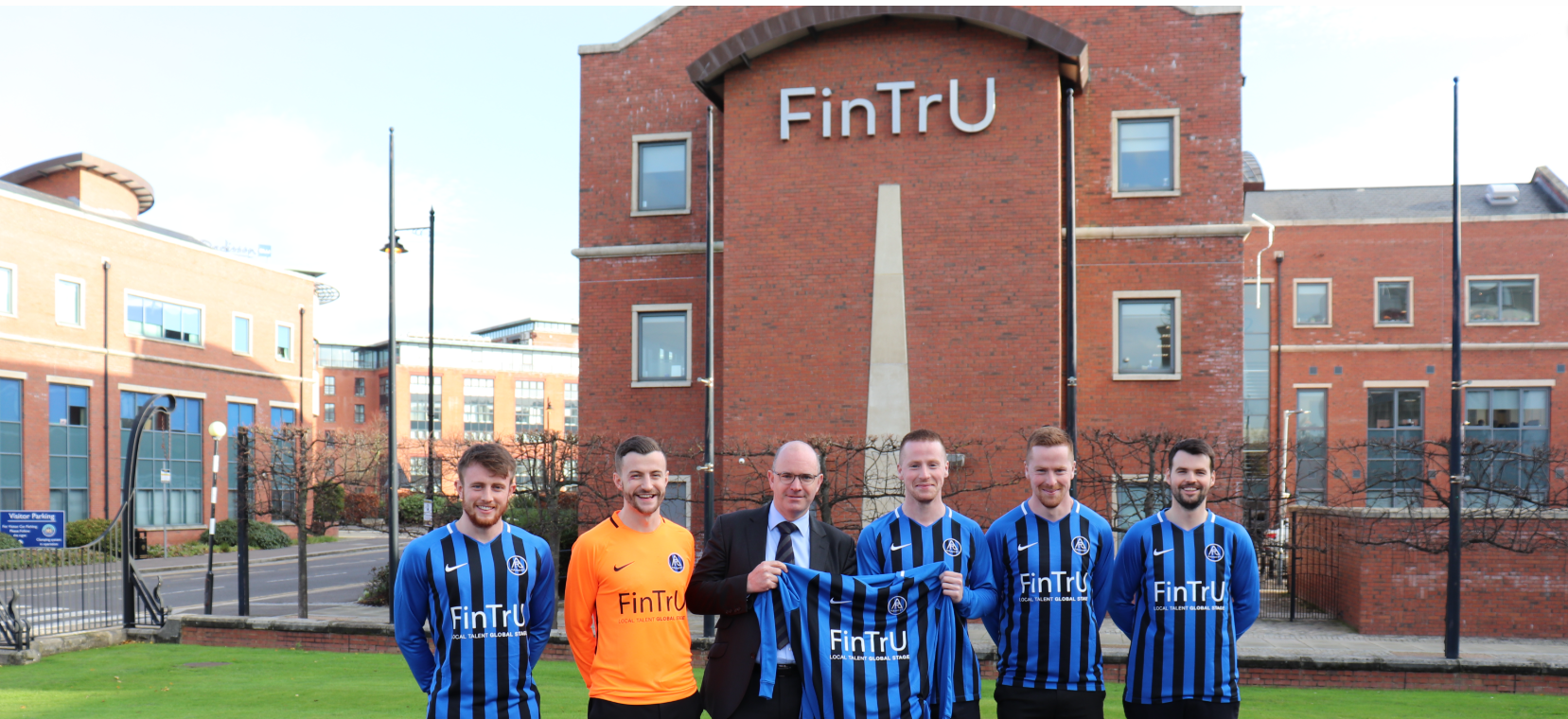 FinTrU CEO with some Aquinas players in front of FinTrU Meter House, holding an Aquinas t-shirt