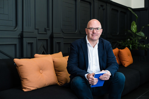 Darragh McCarthy sitting on a sofa with a blue notebook in his hands